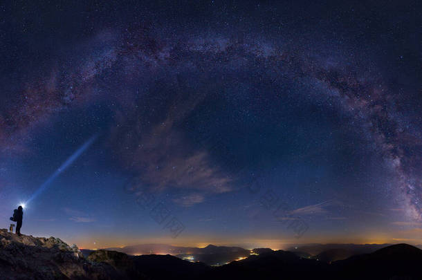 神奇的夜晚，一个头灯人站在风景的上方，望着满天星斗的银河