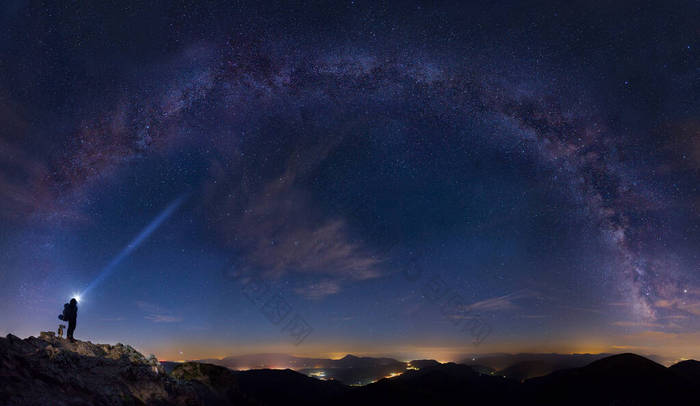 神奇的夜晚，一个头灯人站在风景的上方，望着满天星斗的银河