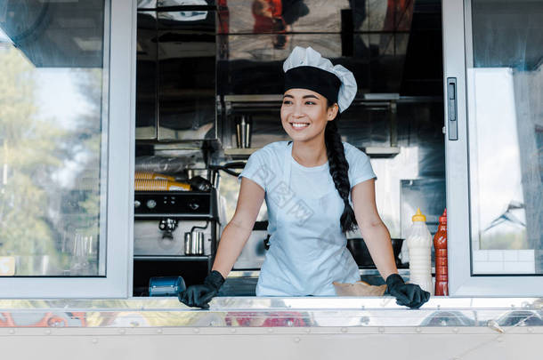 快乐的亚洲女人在帽子和厨师制服微笑在<strong>食品卡</strong>车