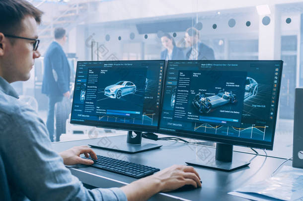 专业工程师使用 3d Cad 软件在计算机上工作，并在高科技开发实验室中测试电动汽车底盘原型，并配有车轮、电池和发动机.