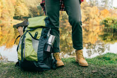 裁剪的图像旅行者的腿与背包在秋天的背景