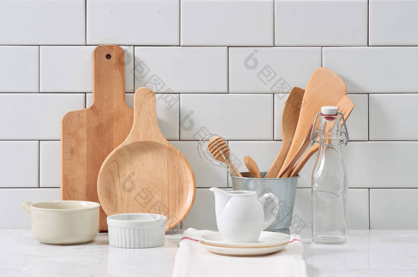 质朴的厨具和陶瓷水罐与木制炊具设置在白色瓷砖背景