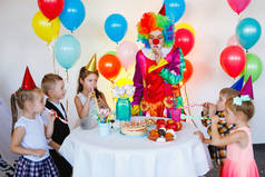 孩子们在生日派对上和小丑玩耍和玩乐.