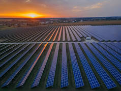 在阳光灿烂的夏日落日下,在一个太阳能农场看到大型太阳能电池板的无人驾驶飞机图像.太阳能电池发电厂，彩色照片