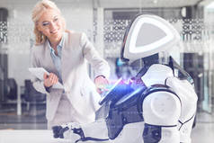 微笑的女商人一边操作机器人一边拿着数字平板电脑，网上演示