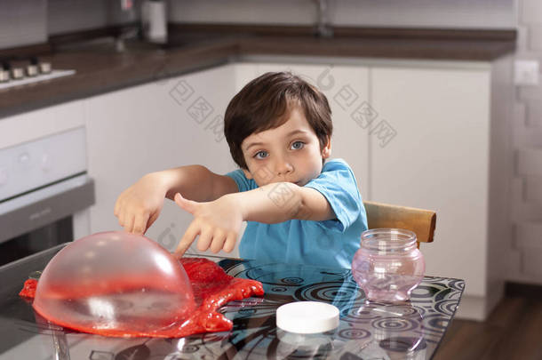 漂亮可爱的小男孩在桌旁玩黏液。巨大的泡泡家孩子们在家里玩乐游戏娱乐
