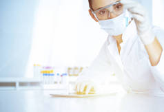女性实验室助理用蓝色液体分析试管.医药、保健和研究概念