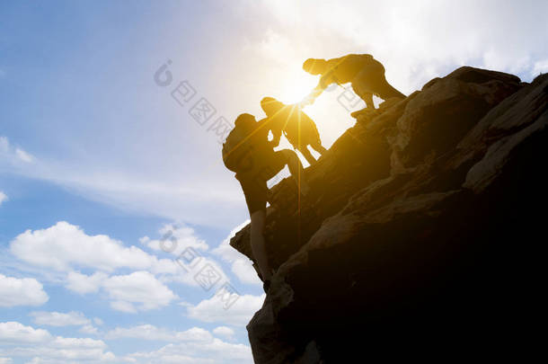 亚洲夫妇徒步旅行互相帮助在山上的<strong>剪影</strong>与阳光。夫妇远足互相帮助<strong>剪影</strong>在山与阳光