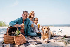 海滩上金黄色回收器附近，家人举杯橙汁的选择性焦点