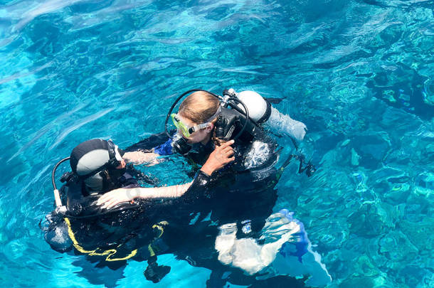 两名潜水员在<strong>黑色</strong>潜水衣, 一个男人和一个女人与氧气瓶下沉在透明的蓝色水的<strong>海洋</strong>, <strong>海洋</strong>在一个热带天堂温暖的度假胜地.