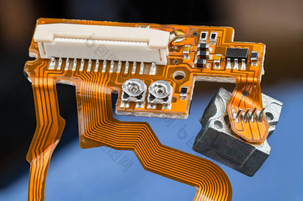 橙色印刷线路板，带有柔性丝带电缆，小电子元件和白色连接器。从数字CD / DVD光盘驱动器内部关闭平面和弯曲PCB 。电子废物处置.