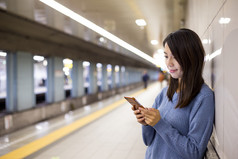 女人在火车平台上使用智能手机