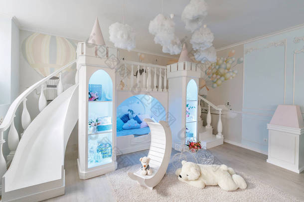 宽敞的儿童房间的内部。装饰城堡与床里面, 游戏滑动和台阶