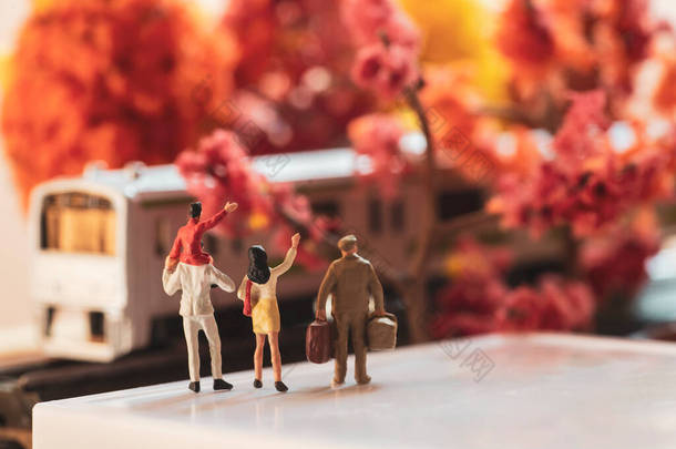 <strong>秋季</strong>或<strong>秋季</strong>在火车站台上等待或挥手的家庭和管家的微型玩具雕像- -采用暖色调过滤器.