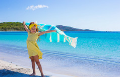 在热带度假期间，小女孩用海滩毛巾玩乐