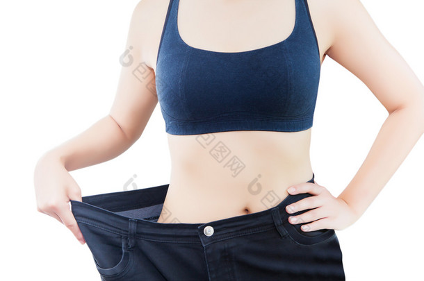 纤细的腰身的年轻女子在大牛仔裤显示成功减肥，白色背景，饮食概念上孤立的特写镜头