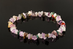 从晶体的紫水晶、 萤石、 碧玉和黑色的桌子上的玫瑰石英特写项链