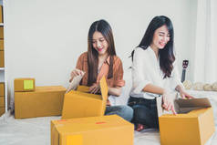 两个年轻的亚洲人创办小企业企业家中小企业分销仓库与邮包信箱。小主人家庭办公室。在线营销和产品包装及配送服务