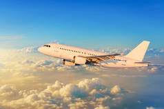 飞翔的飞机在云层之上天际有明亮的日落颜色.
