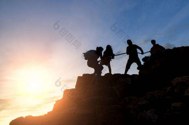 亚洲情侣远足在山上互相帮助剪影与阳光, 夫妇远足互相帮助剪影在山与阳光