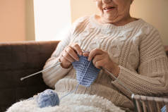 Senior woman knitting warm sock at home