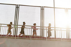 一队年轻的亚裔成年男子和女子在体育场的大看台上奔跑.
