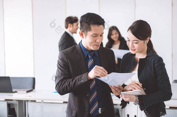 商务团队会议一起到 brainstrom。年轻的亚洲男性与美丽的年轻亚洲妇女站在一起看销售图。年轻一代企业团队理念.
