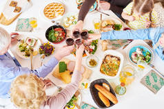 在节日庆祝活动中, 大幸福家庭坐在餐桌上享用美味的自制食物和敬酒的美景