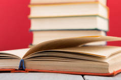 教育和智慧概念.木制桌子打开的书,红色背景
