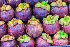 超大尺寸的紫色山竹 (山核桃) 在水果市场出售。关闭有机紫罗兰果实的纹理背景表面.