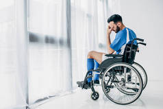 不满的男子穿着足球制服坐在轮椅在医院靠近窗口