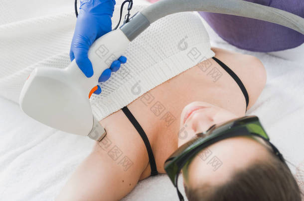 带<strong>防</strong>护眼镜的女性患者在窝窝上进行激光<strong>脱</strong>毛手术的视图