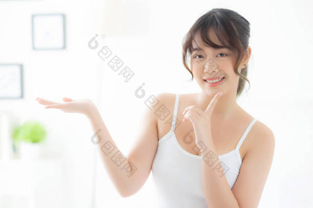 美丽的年轻亚洲女人面带微笑，表现出对皮肤的呵护