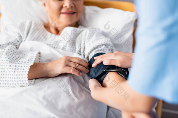 <strong>护士长</strong>袖口固定在老年妇女手臂上的剪影,选择性聚焦