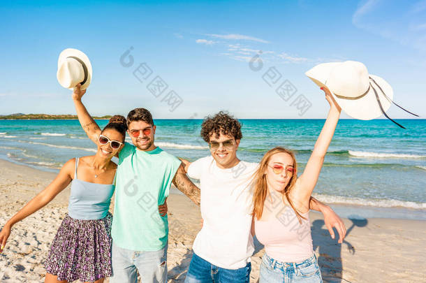 在热带海洋度假胜地的海滨，一群朋友互<strong>相拥</strong>抱，看着摄像机。快乐的学生一起享受海上假期。摆姿势拍照的无忧无虑的人