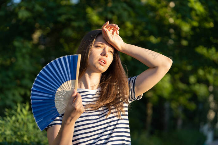 年轻女子在室外中暑.闷热的女孩摸额头很不开心