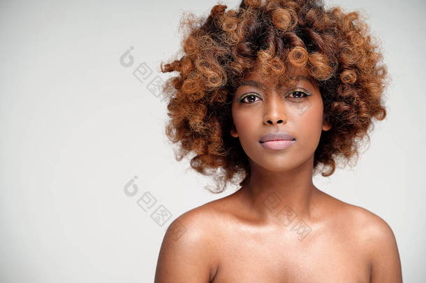 年轻迷人的非洲女人的美丽肖像，有着完美的皮肤和精致迷人的黄眼线妆容。女孩与非洲的发型看着相机。工作室拍摄。大量的复制空间.