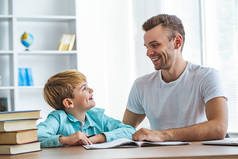 快乐的父亲和一个儿子在办公桌前做作业