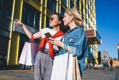 从下面的注意，年轻优雅的女性在一起购物时寻找方向，并在城市地区使用电话寻找路线
