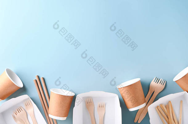 纸杯、碗碟、袋、木叉、吸盘、快餐盒、浅蓝色背景的木制餐具。<strong>环保工艺</strong>纸制餐具.回收和运送食物的概念。把它弄坏了顶部视图