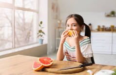 小女孩在厨房吃新鲜柚子