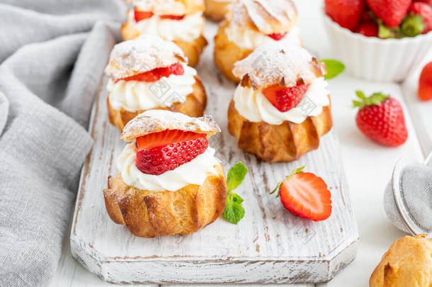 <strong>美味</strong>的自制<strong>小蛋糕</strong>，用奶油、草莓和糖粉装饰在白色的木制背景上。复制空间