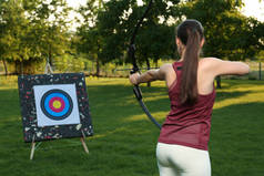 妇女与弓箭瞄准射箭目标在公园，后视镜