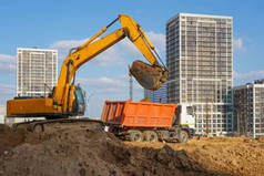 城市多层建筑建筑工地上一台挖掘机和一辆卡车的照片.