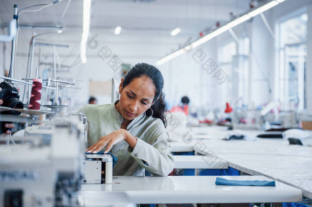 这家工厂的制衣女工在缝纫机上缝衣.