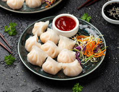 传统的亚洲大虾或虾仁饺子哈考、哈考或哈尔谷类。配菜、胡萝卜沙拉、大豆和甜辣椒酱