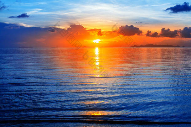 色彩艳丽的海景，明亮的海洋日出，金黄的阳光反射，蓝色的水波，橘红色的天空，云彩，美丽的热带岛屿海滨风景，暑假，度假，旅游