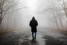 雾的风景。在雾蒙蒙的可怕道路上独自行走的人.