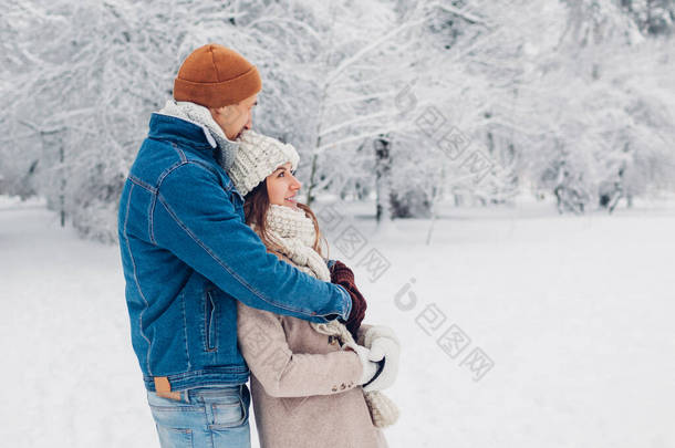 年轻貌美的恋人在冬季公园散步.在户外欣赏雪景的男女拥抱