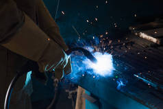 Cropped view of welder in gloves working with torch in factory